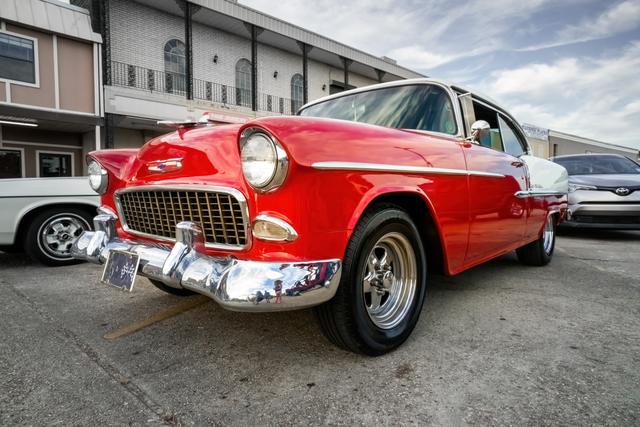 Red 1955 Chevrolet Bel Air with chrome bumper at a car show