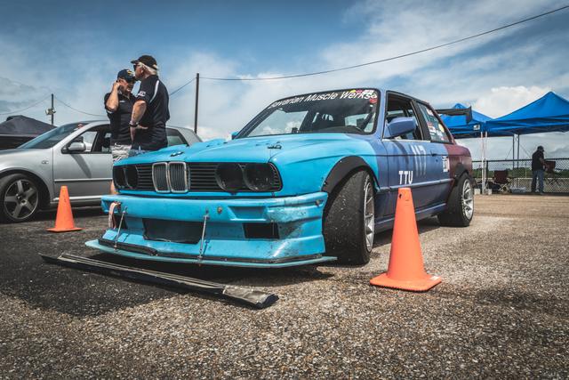Blue BMW E30 race car among orange cones at a track day