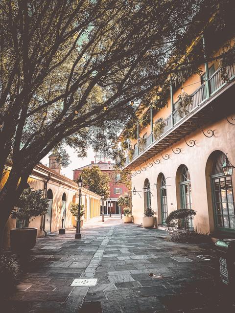 A quiet flagstone alley with arched doorways and iron balconies in the French Quarter, New Orleans